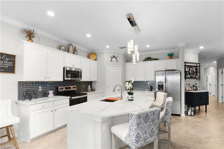 Kitchen featuring tasteful backsplash, sink, stainless steel appliances, and decorative light fixtures
