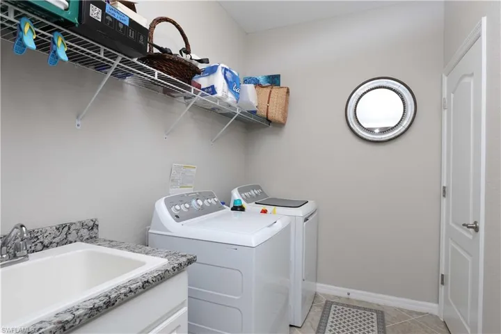 Laundry room featuring sink, light tile patterned floors, and independent washer and dryer