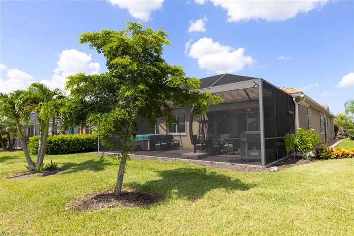 Rear view of house featuring a lanai, a patio, and a yard