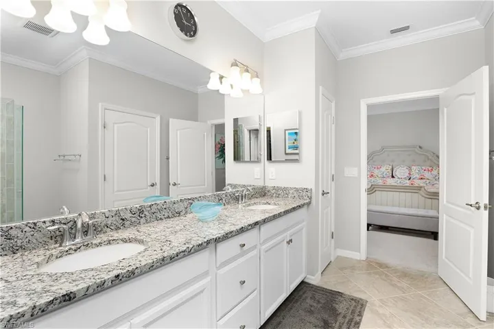 Bathroom featuring double sink vanity, crown molding, and tile patterned flooring