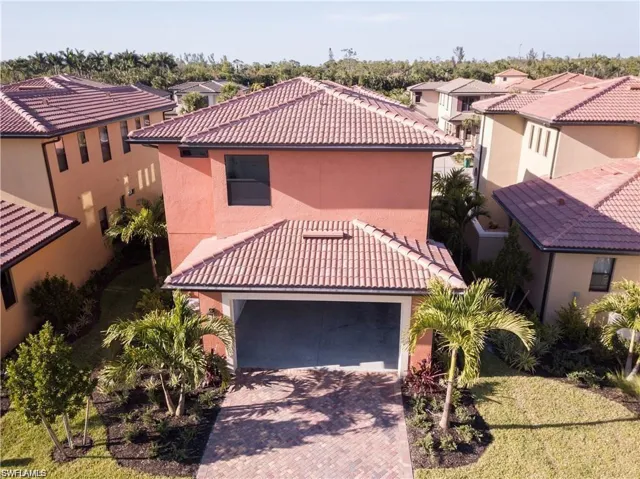 Mediterranean / spanish home with a tile roof, stucco siding, an attached garage, a residential view, and decorative driveway