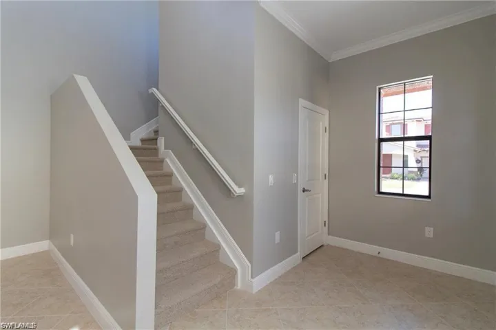 Stairway with tile patterned floors, crown molding, and baseboards