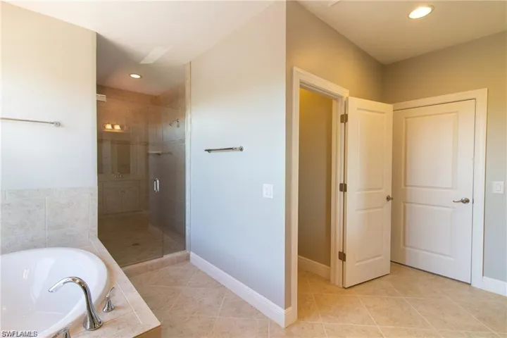 Bathroom with baseboards, a garden tub, and a shower stall