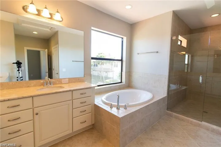 Full bath with a stall shower, tile patterned floors, vanity, a garden tub, and recessed lighting