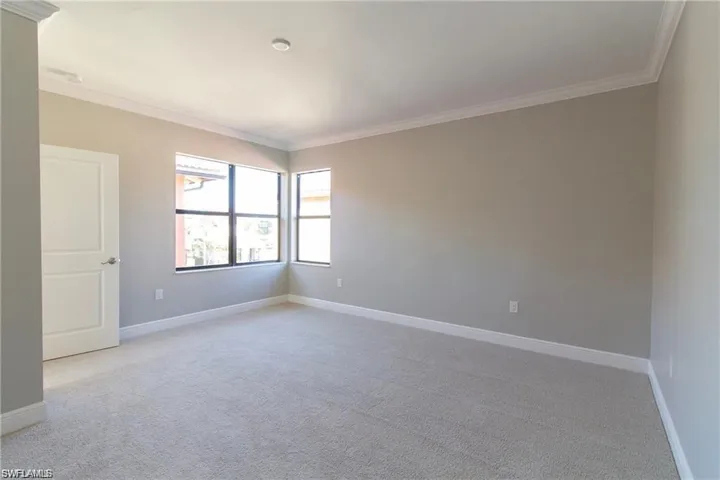 Empty room with baseboards, crown molding, and light colored carpet