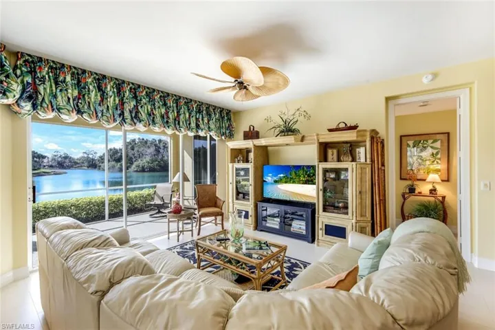 Tiled living room featuring a ceiling fan and a water view