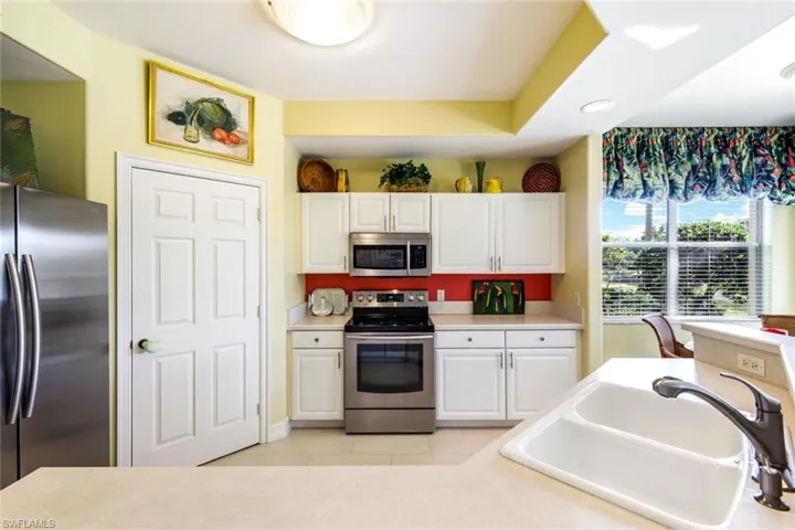 Kitchen with stainless steel appliances, white cabinetry, light countertops, and light tile patterned floors
