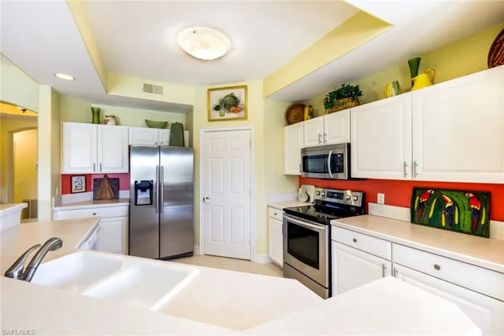 Kitchen featuring stainless steel appliances, white cabinetry, light countertops, and recessed lighting