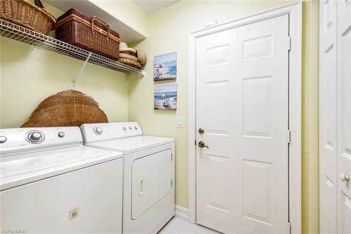 Laundry area with independent washer and dryer and light tile patterned floors
