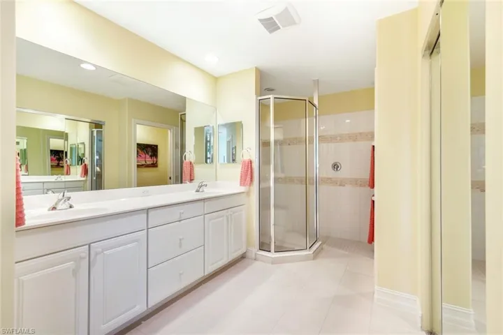 Full bath with double vanity, a stall shower, light tile patterned floors, and recessed lighting