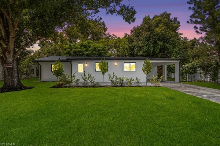 Single story home with a front lawn, concrete driveway, a carport, and a porch