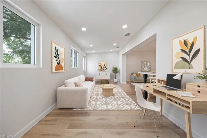 Living room with light wood-style flooring, a desk, and recessed lighting