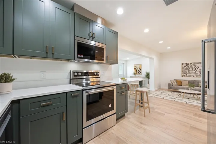 Kitchen featuring stainless steel appliances, recessed lighting, light wood-type flooring, green cabinetry, and light stone countertops