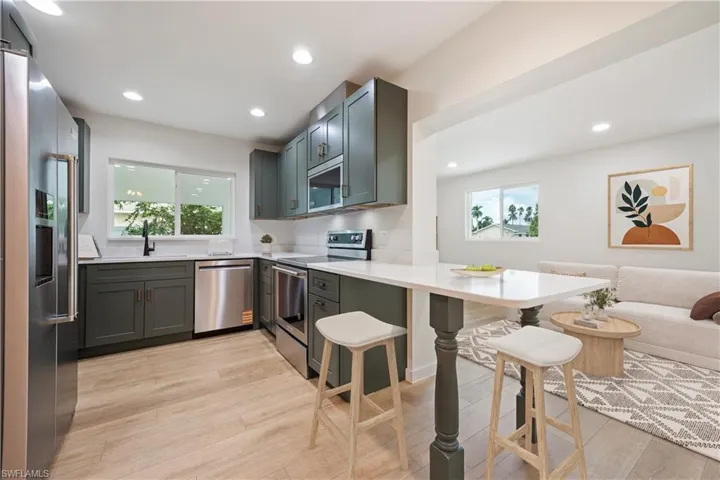 Kitchen with appliances with stainless steel finishes, recessed lighting, light wood-type flooring, a peninsula, and a kitchen bar