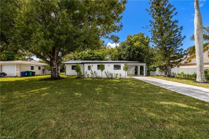 Ranch-style house with a front lawn, concrete driveway, and a carport