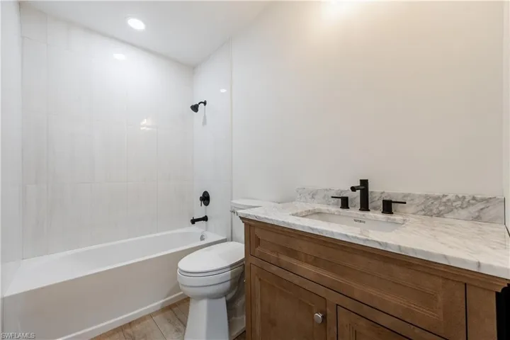 Bathroom with vanity, shower / tub combination, and light wood-style flooring