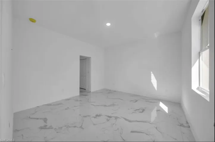 Empty room featuring light marble finish flooring and recessed lighting
