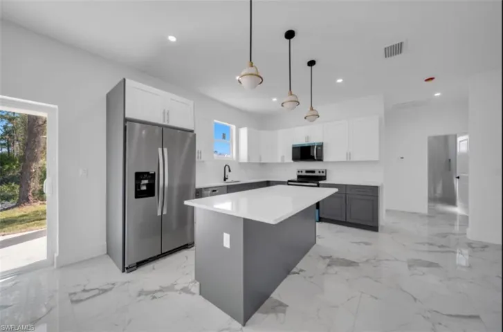 Kitchen featuring gray cabinets, stainless steel appliances, pendant lighting, white cabinetry, and a center island