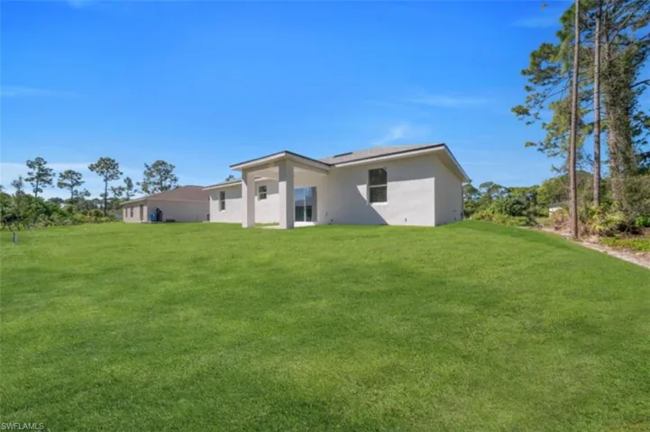 Rear view of property featuring a yard and stucco siding