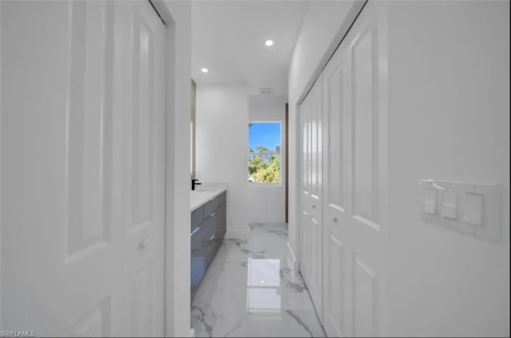 Bathroom with a closet, vanity, light marble finish flooring, and recessed lighting