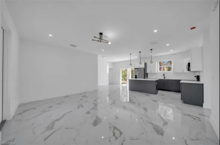 Unfurnished living room featuring recessed lighting and light marble finish floors