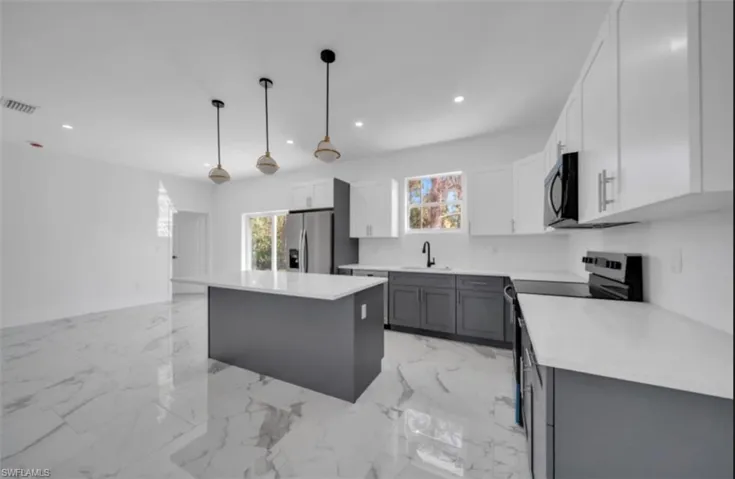 Kitchen with electric range, light marble finish flooring, white cabinets, recessed lighting, and healthy amount of natural light