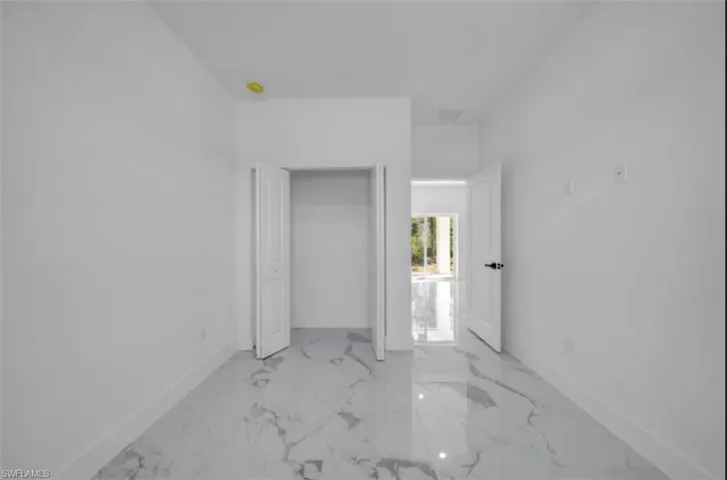 Unfurnished bedroom with baseboards and light marble finish flooring