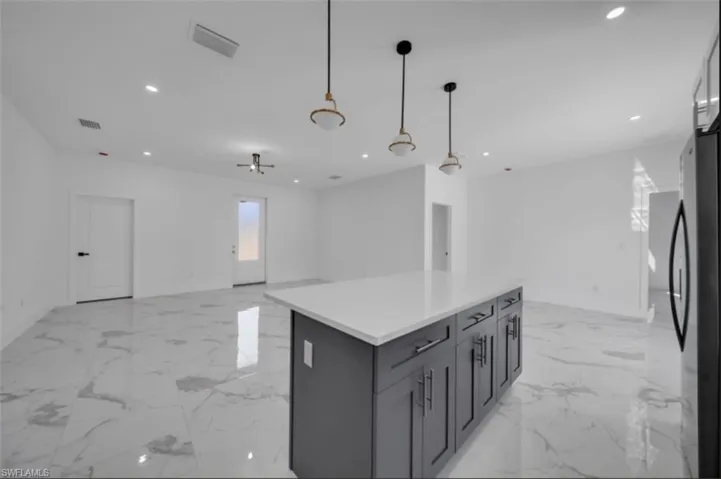 Kitchen featuring open floor plan, freestanding refrigerator, decorative light fixtures, recessed lighting, and a center island