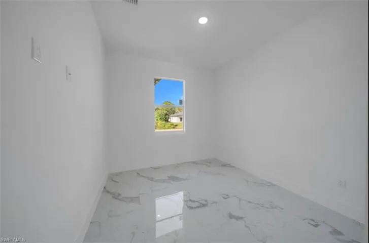 Empty room with light marble finish floors and recessed lighting