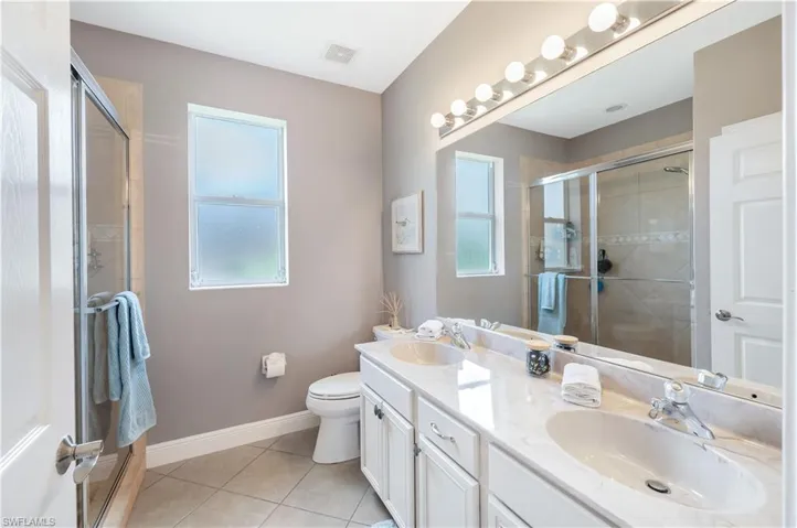 Bathroom with tile patterned flooring, double vanity, and a tile shower