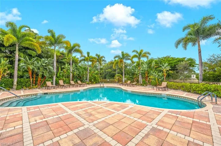 Community pool with a patio area and view of scattered trees