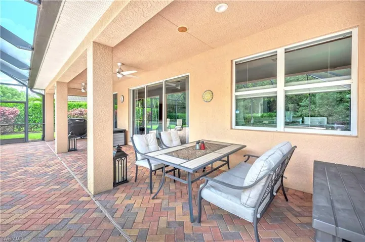 View of patio / terrace with outdoor dining space, a ceiling fan, and glass enclosure
