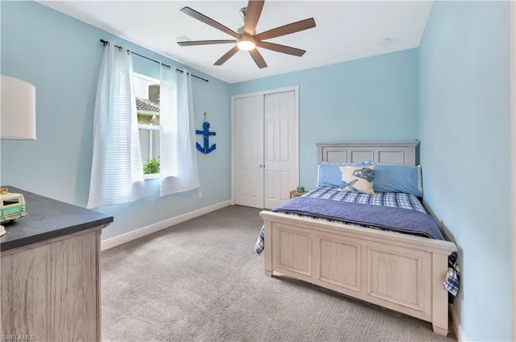 Bedroom with light carpet, a closet, and a ceiling fan