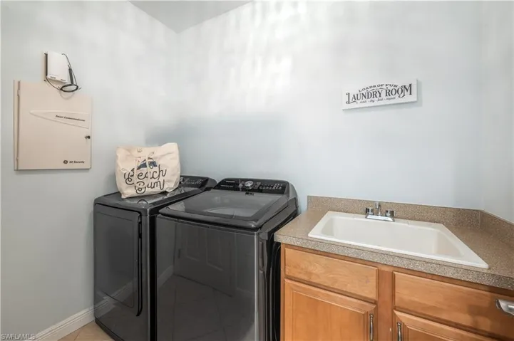 Washroom featuring independent washer and dryer, cabinet space, and light tile patterned flooring