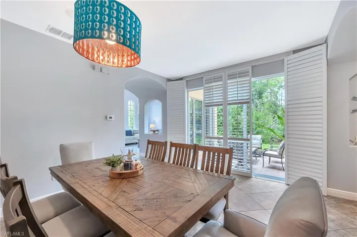 Dining space featuring arched walkways and light tile patterned floors