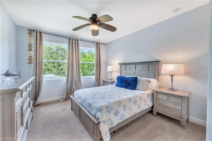 Bedroom with light colored carpet and a ceiling fan