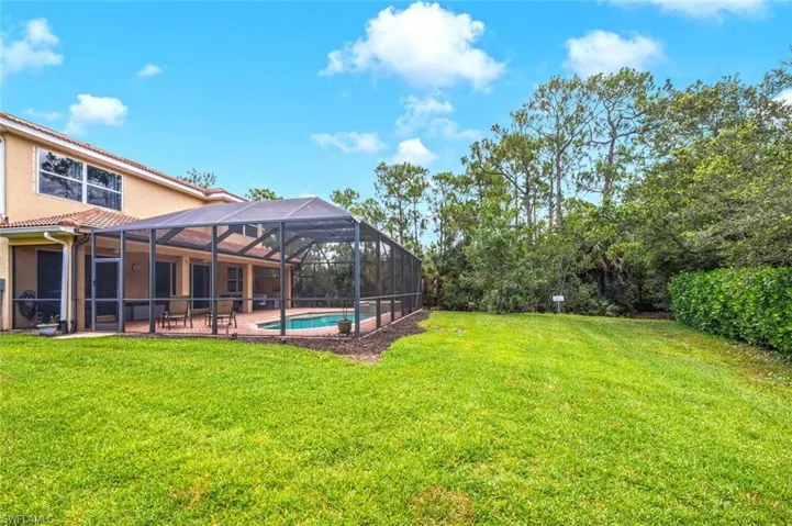 View of grassy yard featuring a patio, an outdoor pool, and a lanai
