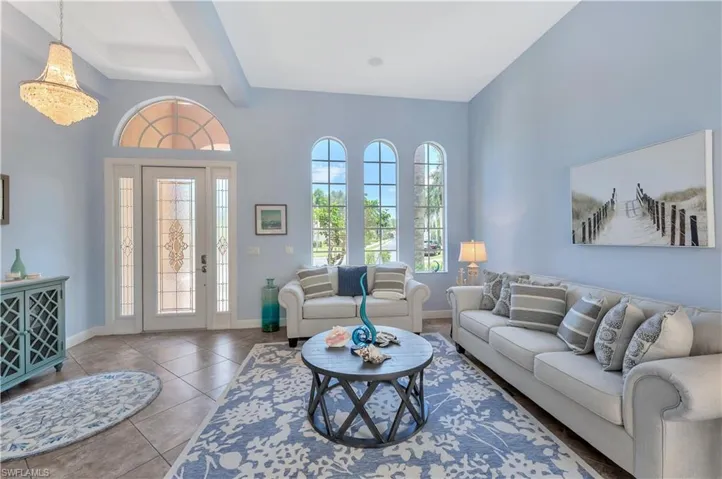 Living room featuring tile patterned floors, beamed ceiling, and a towering ceiling