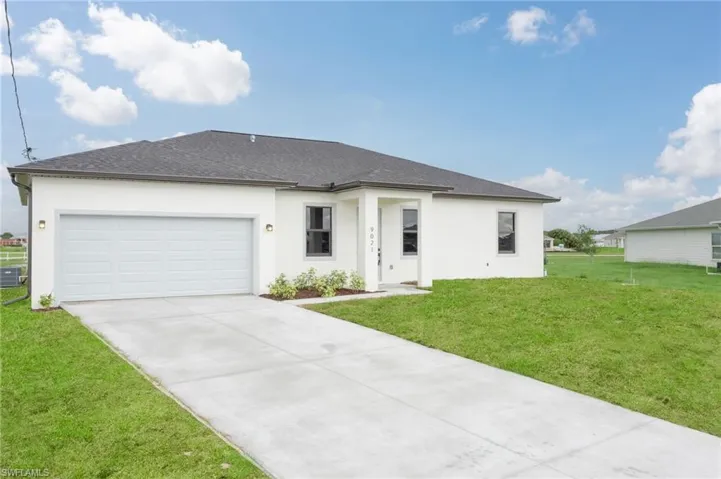 View of front of home with a garage, a front lawn, and central air condition unit