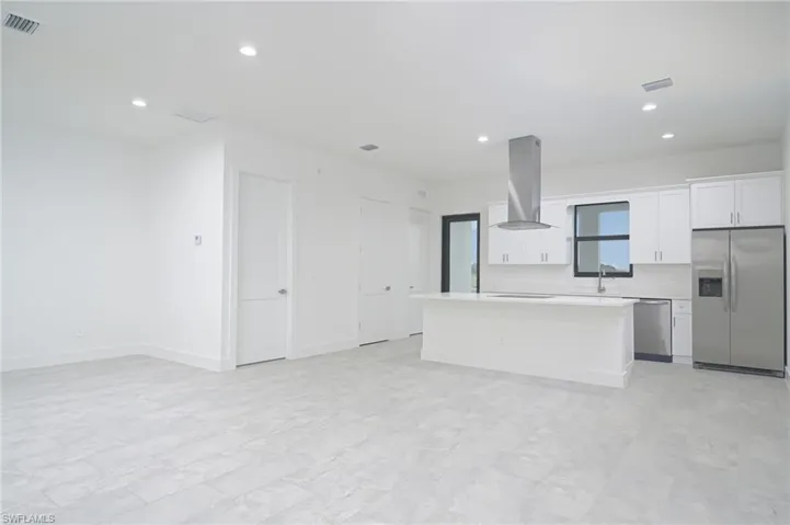 Kitchen with white cabinets, appliances with stainless steel finishes, fume extractor, and light tile flooring