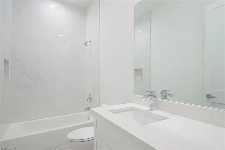Full bathroom featuring tiled shower / bath, vanity, and toilet