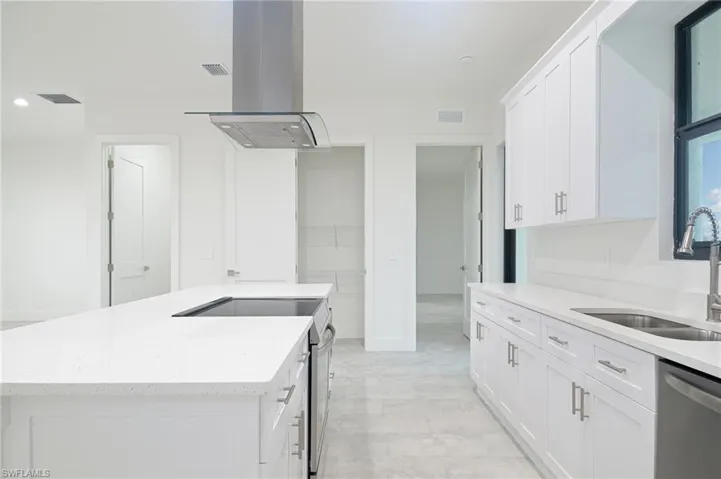 Kitchen with range with electric cooktop, island range hood, dishwasher, light tile floors, and white cabinets