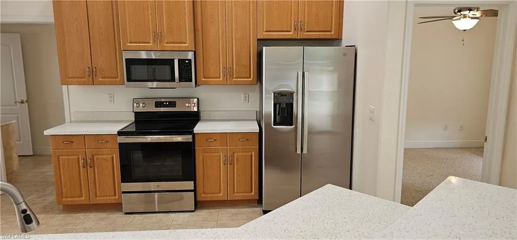 Kitchen with ceiling fan, stainless steel appliances, and light tile patterned floors