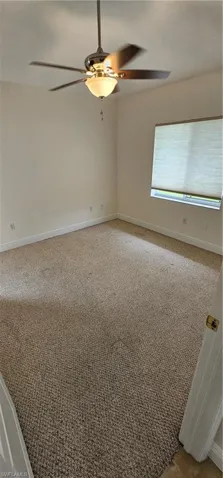Carpeted spare room with ceiling fan