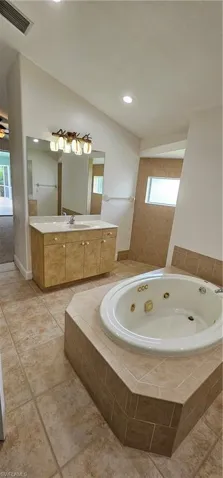 Bathroom with tiled bath, tile patterned floors, and a healthy amount of sunlight