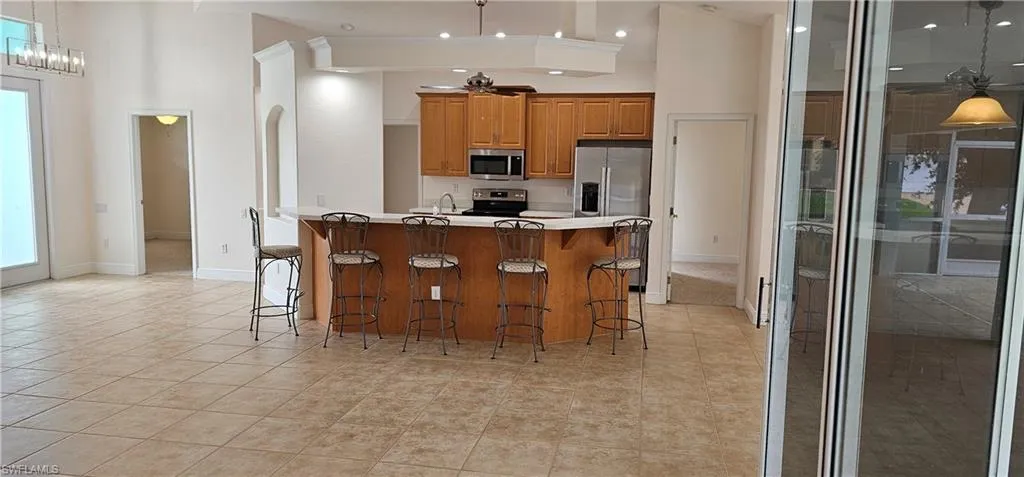 Kitchen with a breakfast bar area, a towering ceiling, appliances with stainless steel finishes, and light tile patterned floors