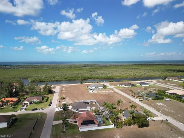 Aerial view of residential area with a large body of water and a heavily wooded area