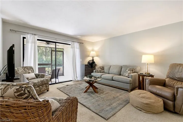 Living area with light colored carpet and a ceiling fan