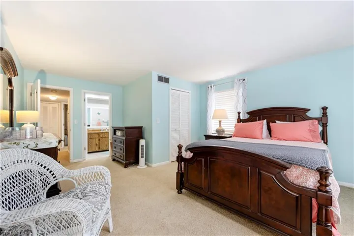 Bedroom with a closet, light colored carpet, and ensuite bathroom