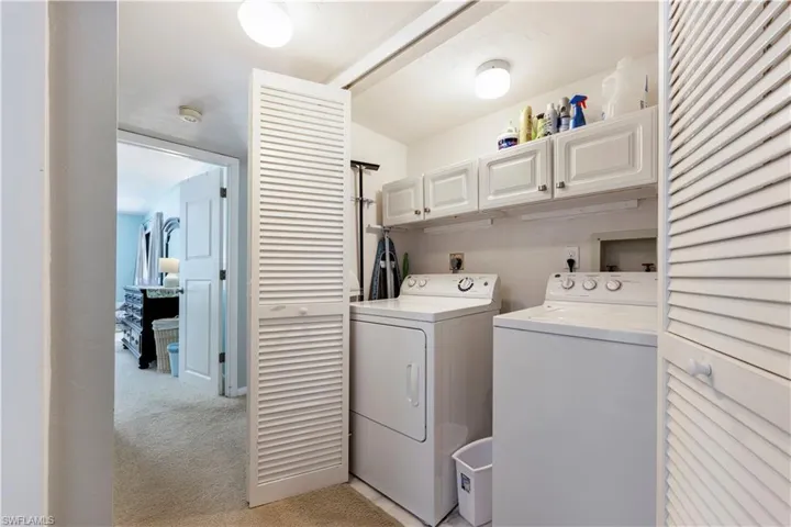 Laundry room with cabinet space, washer and dryer, and light carpet